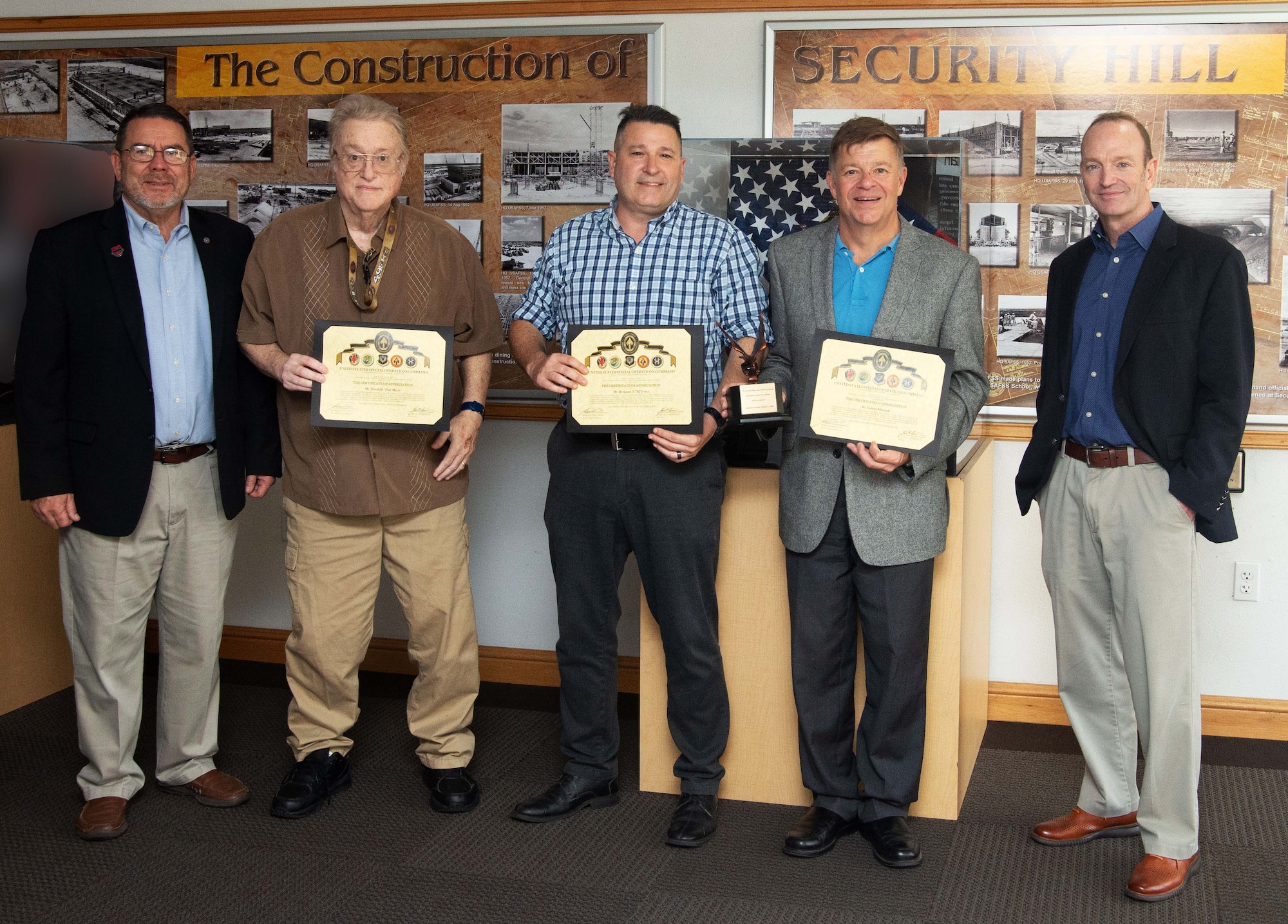 Five men stand in a line holding certificates.