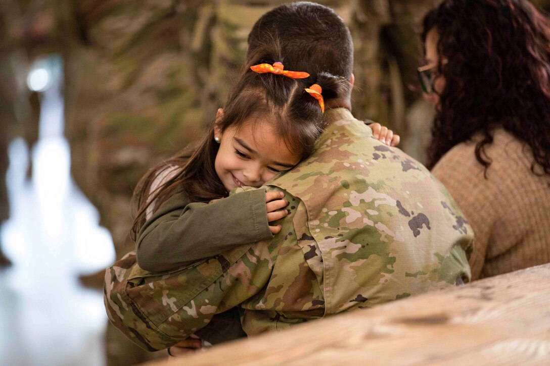 A child hugs a soldier.