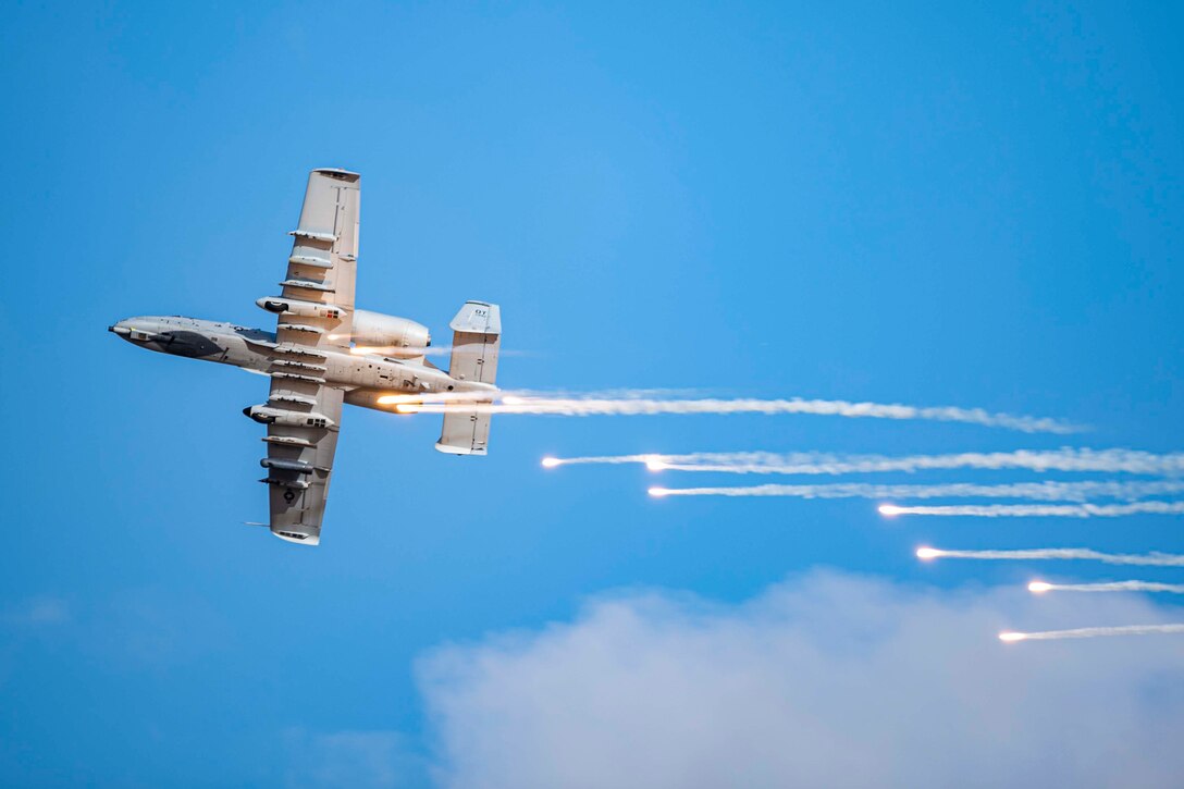 Flares fire from the back of an airborne aircraft.