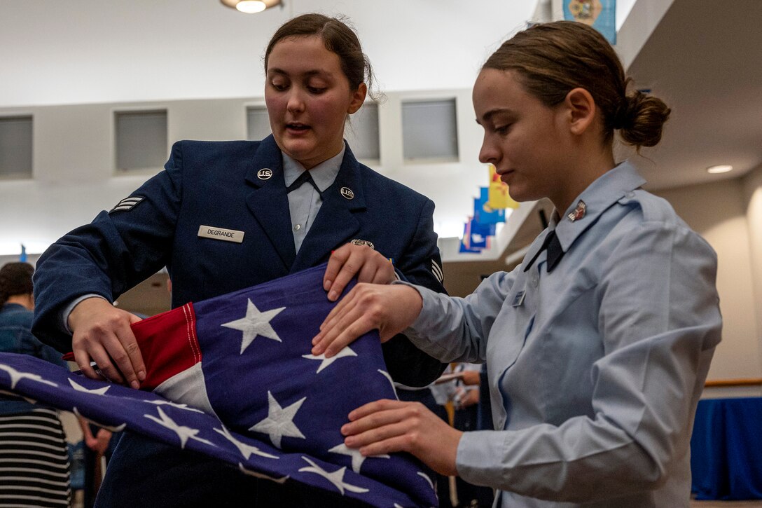 An airman and a Civil Air Patrol cadet fold a U.S. flag together.