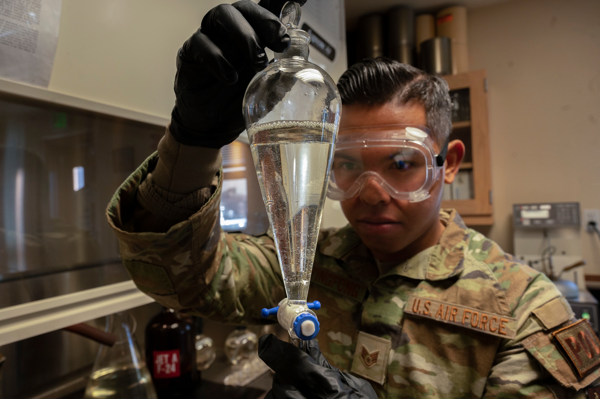 U.S. Air Force Staff Sgt. Austin Taitingfong, 49th Logistics Readiness Squadron fuels laboratory noncommissioned officer in charge, inspects a flask of jet fuel at Holloman Air Force Base, New Mexico, Dec. 12, 2022. The 49th LRS fuels laboratory is the first line of defense for fuel quality control for all organizations on base. (U.S. Air Force photo by Airman 1st Class Isaiah Pedrazzini)