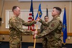 Col. Chris Sigler, commander, 167th Airlift Wing, passes the guideon to Capt. Aaron Hansrote, signifying Hansrote’s new role as 167th Comptroller Flight commander during a change of command ceremony at the 167th base dining facility, Martinsburg, West Virginia, Dec. 3, 2022. Hansrote took command of the flight, previously commanded by Lt. Col James Domenico.
