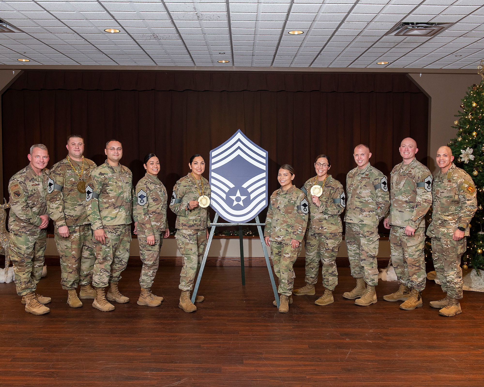 Six men and four women pose with a giant version of the chief master sergeant rank insignia.