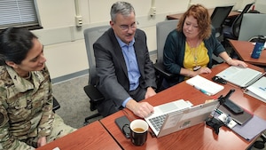 Photo of three people sitting around a computer.
