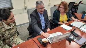 Photo of three people sitting around a computer.