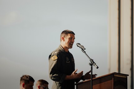 Sailor in a flight suit speaking at a podium