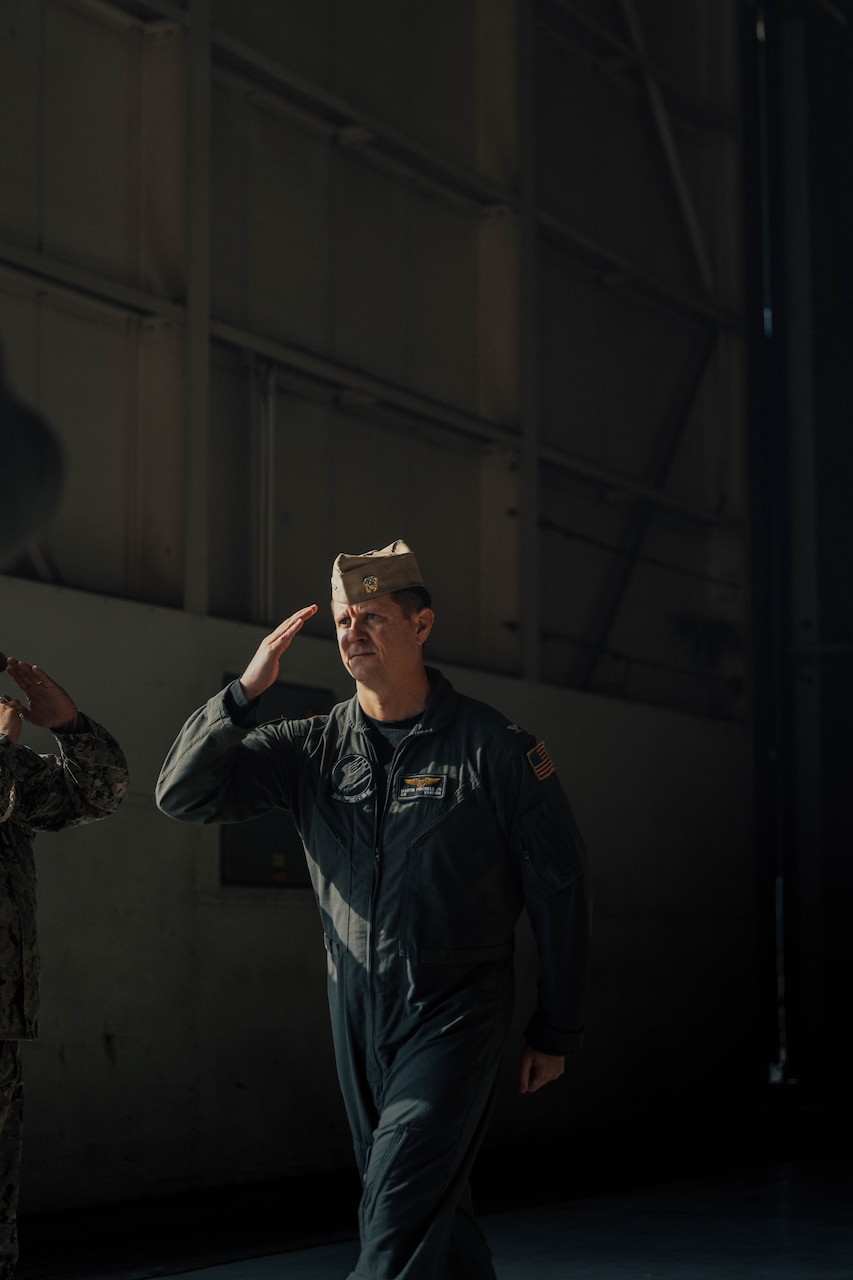 Sailor in flight suit walking and saluting.