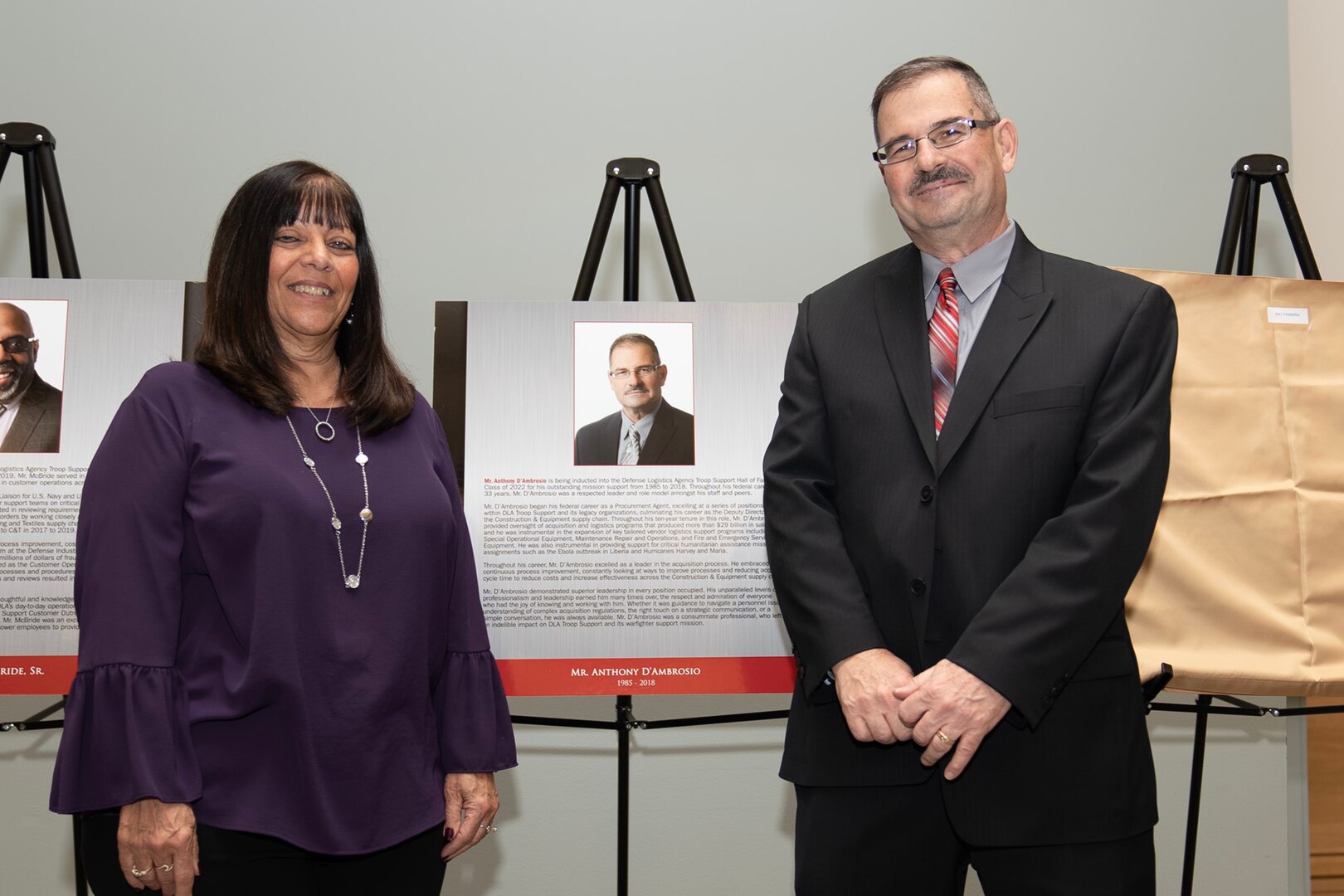man and woman stand next to plaque on stage