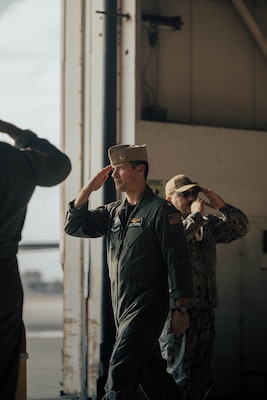 Sailors in a flight suit saluting while walking