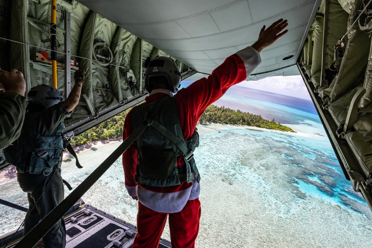Senior Airman Janealle Hogans and Master Sgt. Luke McLimans, 36th Expeditionary Airlift Squadron C-130J loadmasters, wave to island community members on Fananu atoll in the state of Chuuk, Federated States of Micronesia