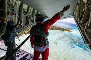 Senior Airman Janealle Hogans and Master Sgt. Luke McLimans, 36th Expeditionary Airlift Squadron C-130J loadmasters, wave to island community members on Fananu atoll in the state of Chuuk, Federated States of Micronesia