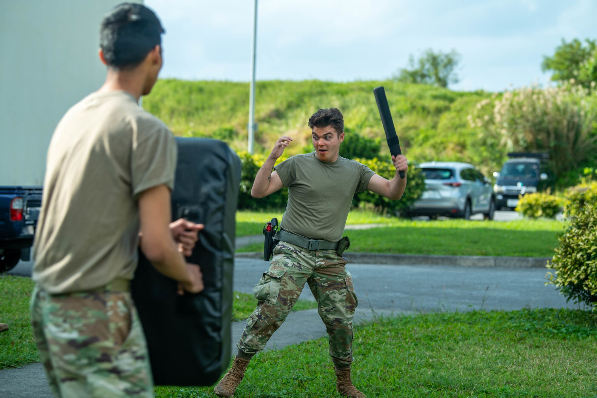 A defender raises a baton to hit a training bag.