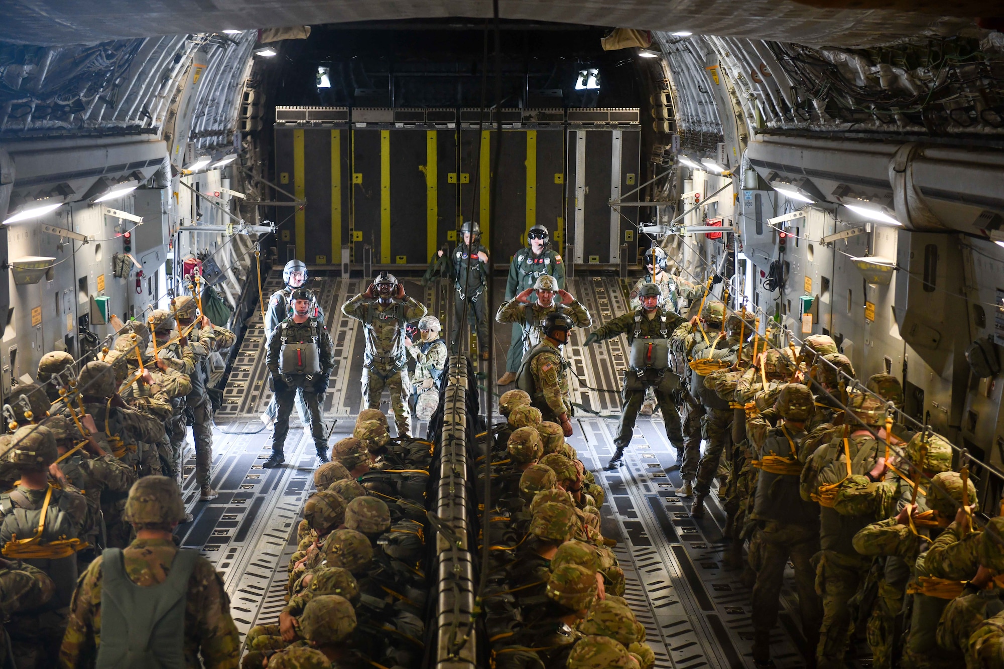 Jumpmasters from both the U.S. and Poland brief the military members how much time they have until their jump over the Sicily Drop Zone near Fayetteville, North Carolina, Dec. 8, 2022. Everyone participating in the jumps for Operation Toy Drop brought toys to donate to children to open during the holiday season. (U.S. Air Force photo by Airman 1st Class Kari Degraffenreed)