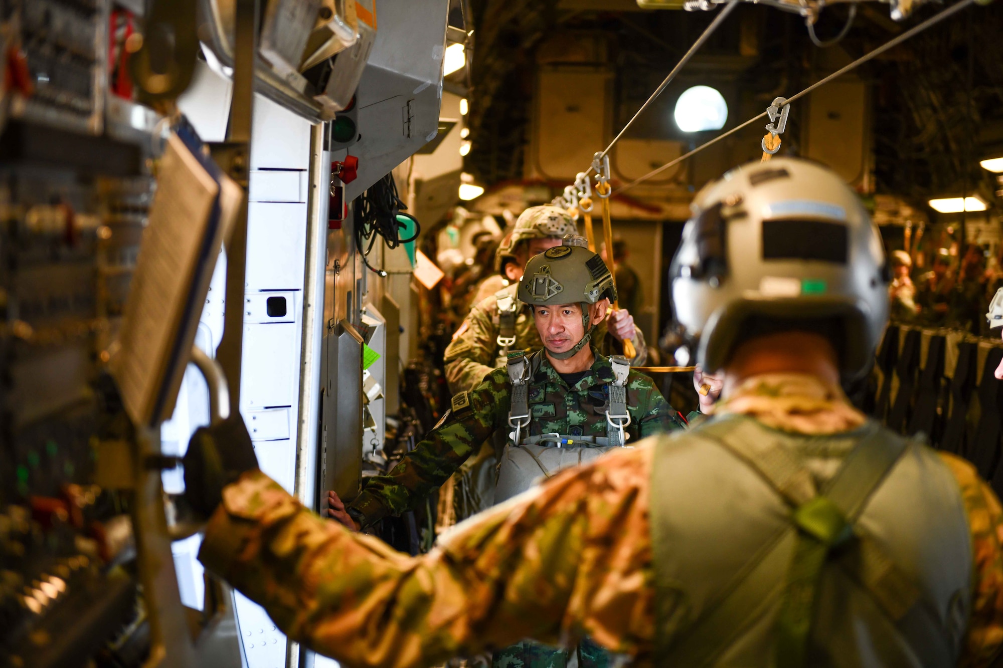 A jumpmaster from Thailand’s military waits inside a C-17 Globemaster III as it flies closer to the Sicily Drop Zone near Fayetteville, North Carolina, Dec. 9, 2022. The second day of the operation included military members from Thailand acting as jumpers and jumpmasters. (U.S. Air Force photo by Airman 1st Class Kari Degraffenreed)