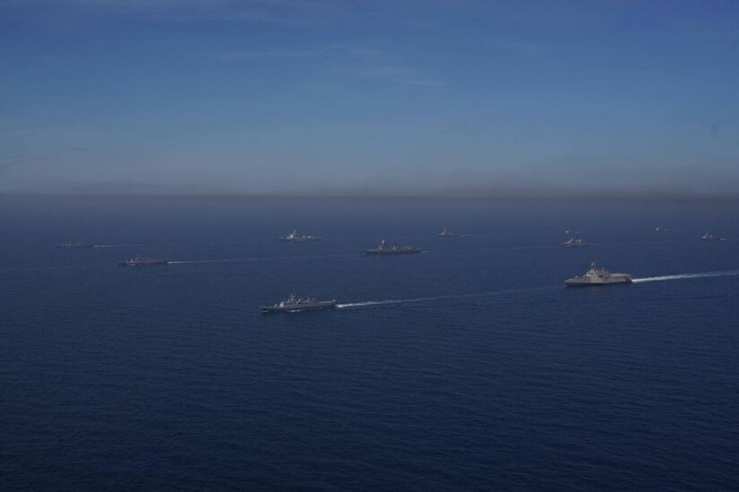 Ships sail in formation in the ocean.