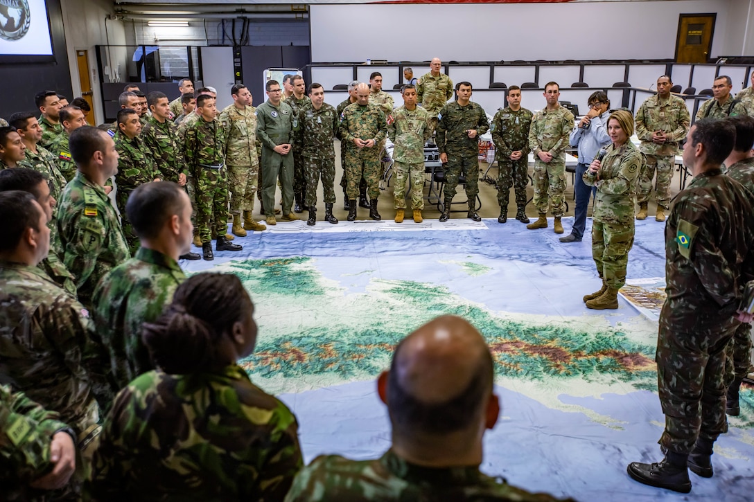General addresses exercise participants while standing on a huge map of Central America.