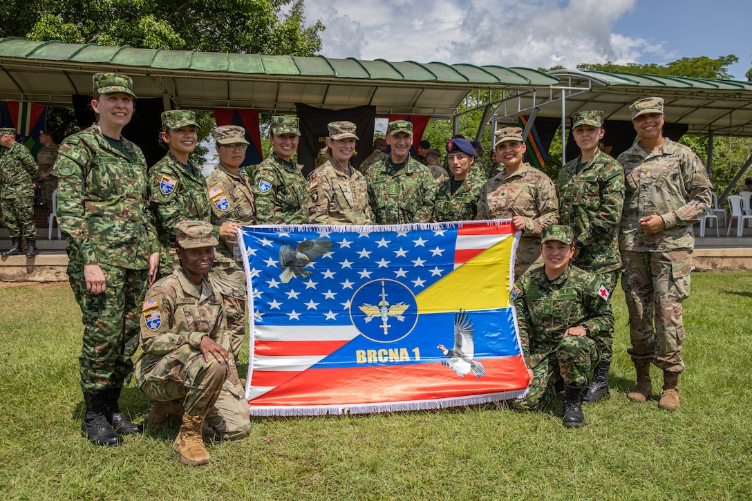 General poses behind a U.S.-Colombian flag with soldiers.