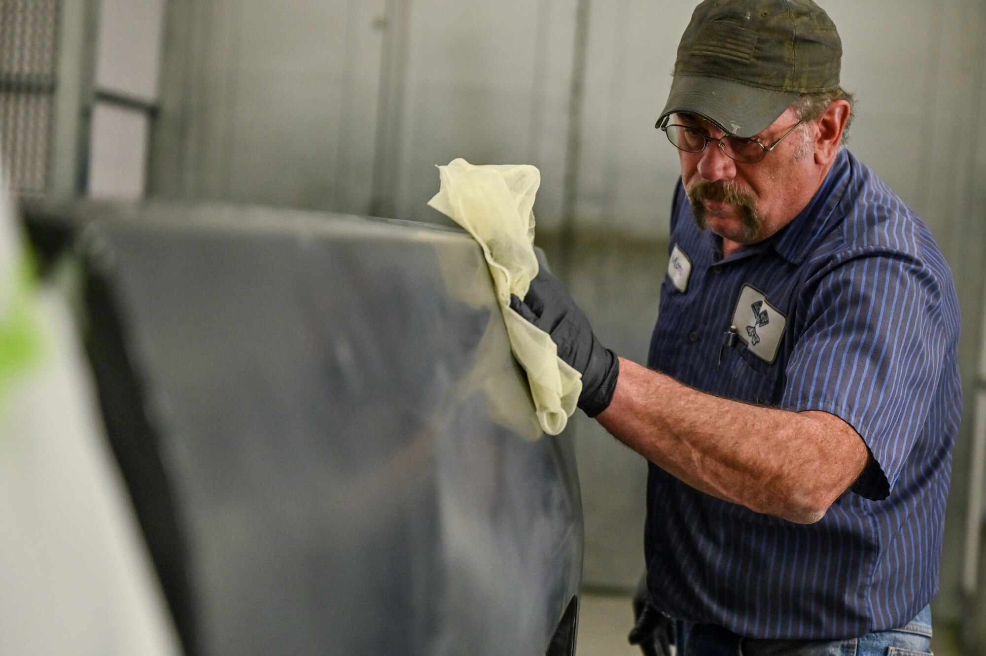 Thomas Hoadley, 90th Logistics Readiness Squadron mobile metal mechanic, cleans the surface to prepare to apply a sealant to a Ford truck rear panel on F.E. Warren Air Force Base, Wyoming, Nov. 29, 2022. With more than 40 years of experience, the 90 LRS Monster Garage or body shop team is repairing the 90th Missile Wing fleet while supporting the Air Force Global Strike priority of people by finding ways to train the next generation of Airmen and find innovative solutions. (U.S. Air Force photo by Joseph Coslett Jr.)