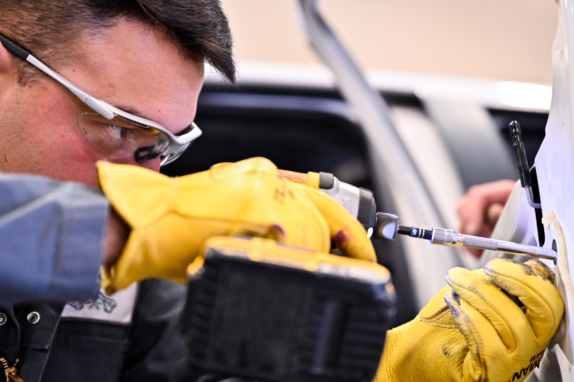 Airman 1st Class Marcos Orellana, 90th Logistics Readiness Squadron vehicle maintenance technician, removes a bolt from a Ford truck's rear passenger door to replace the door after it was damaged on F.E. Warren Air Force Base, Wyoming, Nov. 29, 2022. Orellana is assigned to the body shop to learn basic skills he can use on future deployments. With more than 40 years of experience, the 90 LRS Monster Garage or body shop team is repairing the 90th Missile Wing fleet while supporting the Air Force Global Strike priority of people by finding ways to train the next generation of Airmen and find innovative solutions. (U.S. Air Force photo by Joseph Coslett Jr.)
