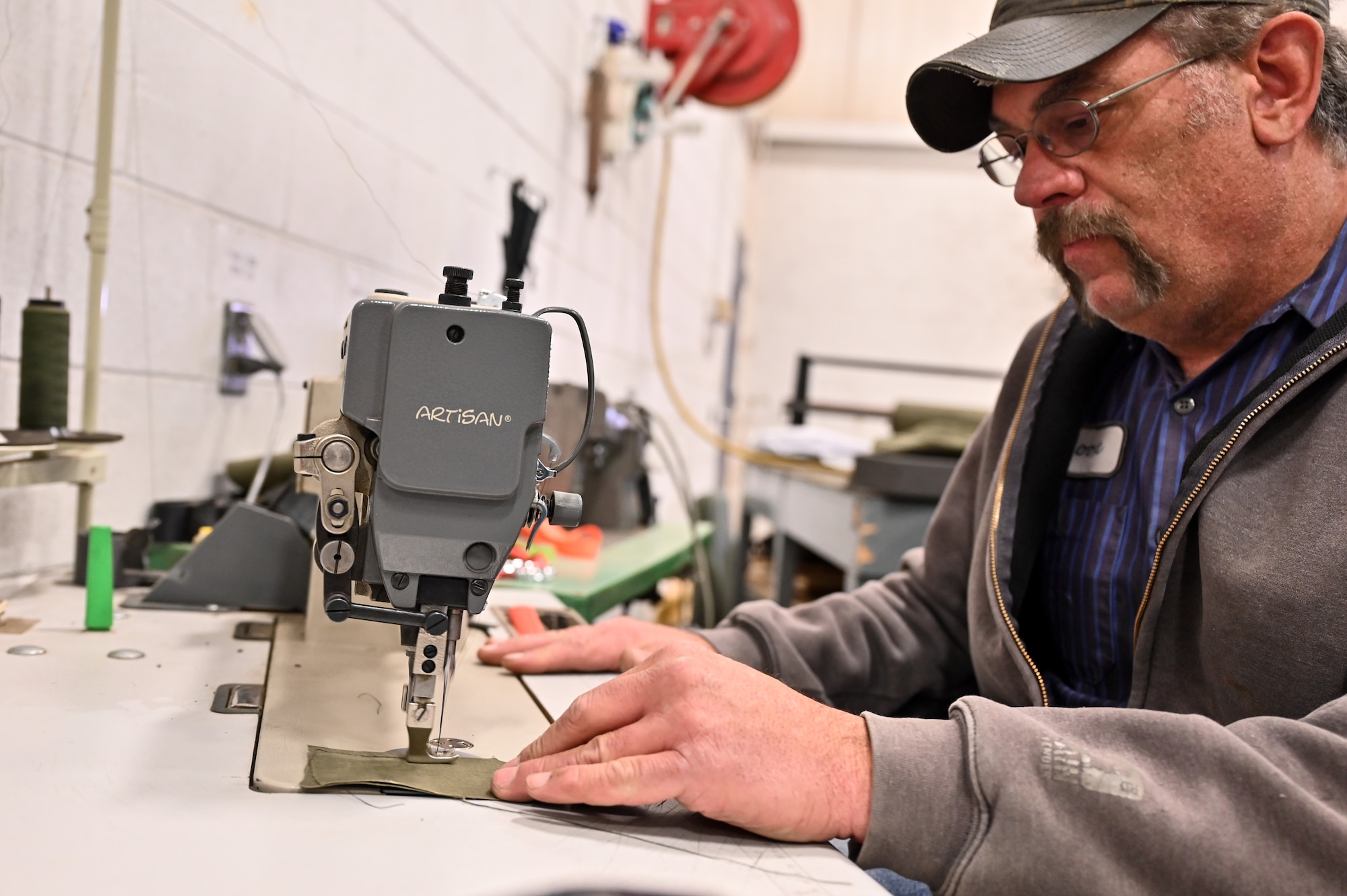 Thomas Hoadley, 90th Logistics Readiness Squadron mobile metal mechanic, sews a piece of fabric used to repair humvee seats on F.E. Warren Air Force Base, Wyoming, Nov. 29, 2022. With more than 40 years of experience, the 90 LRS Monster Garage or body shop team is repairing the 90th Missile Wing fleet while supporting the Air Force Global Strike priority of people by finding ways to train the next generation of Airmen and find innovative solutions. (U.S. Air Force photo by Joseph Coslett Jr.)