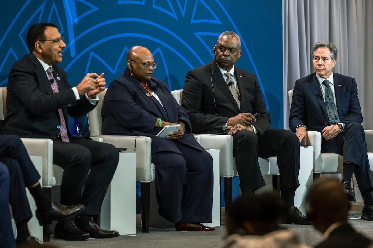 Four individuals are seated on a stage.