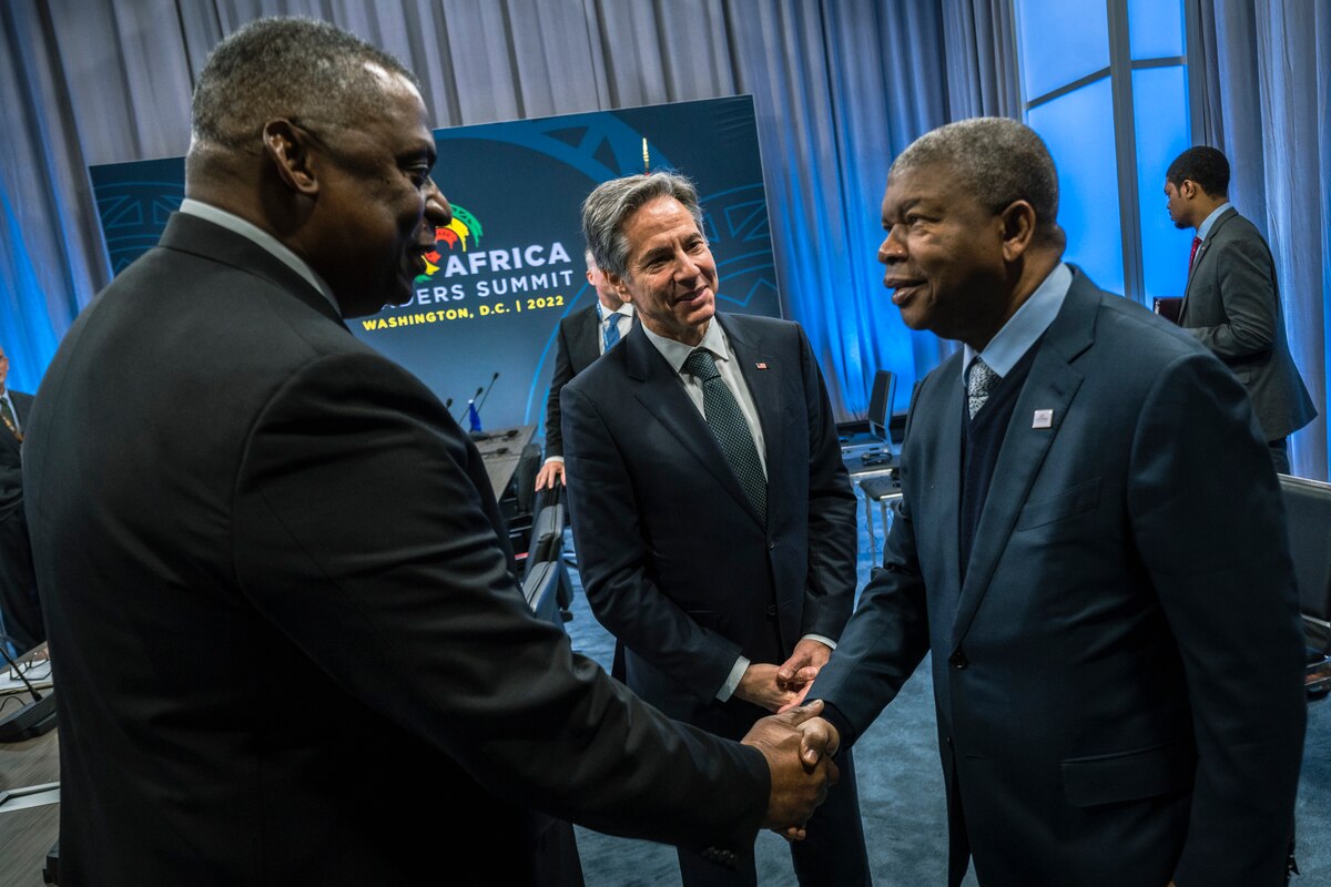 Two men shake hands. Another man stands nearby.