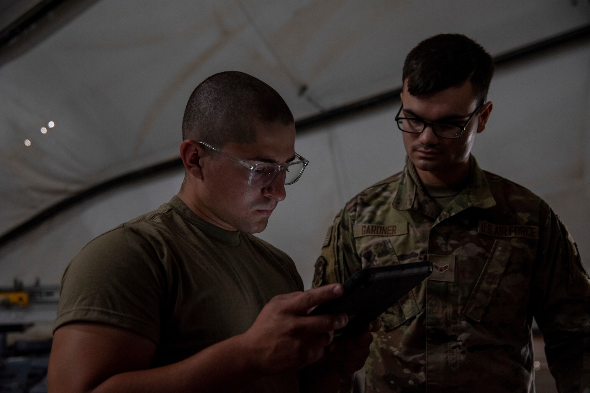 Airman 1st Class Gabriel Lara, 332d Expeditionary Fighter Squadron Maintenance specialist, shows a diagnostic tablet to Senior Airman Elijah Gardner, 332d Expeditionary Civil Engineer Programs specialist, as part of "Maintainer for a Day" at an undisclosed location, Southwest Asia, Nov. 25, 2022. "Maintainer for a Day" is a program that allows Airmen from diverse career fields to experience what it’s like to perform maintenance and repair work on an aircraft. (U.S. Air Force photo by: Tech. Sgt. Jim Bentley)