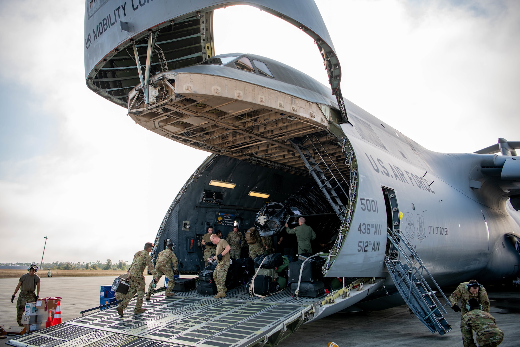 Uniformed members load aircraft into bigger aircraft.