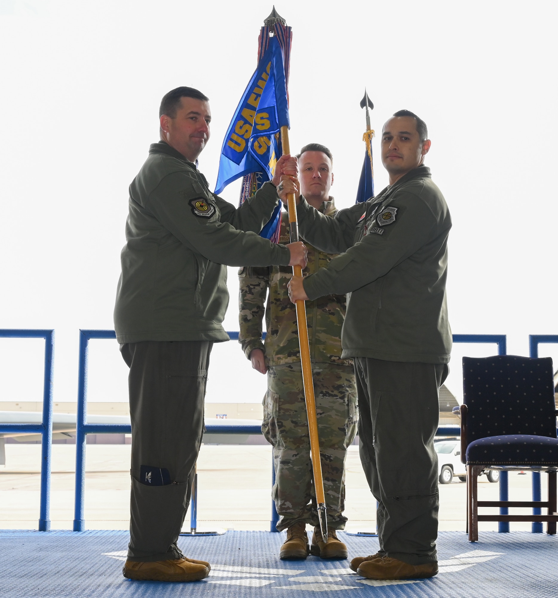 Lt. Col. Marcus Antonini, previous 325th Weapons Squadron, 57th Wing (right), relinquishes command with the guidon to Col. Daniel Lehoski, United States Air Force Weapons School Commandant (left), at Whiteman Air Force Base, Missouri, December 14, 2022. The guidon represents the authority of a commander that is passed on to another. (U.S. Air Force photo by Airman 1st Class Joseph Garcia)
