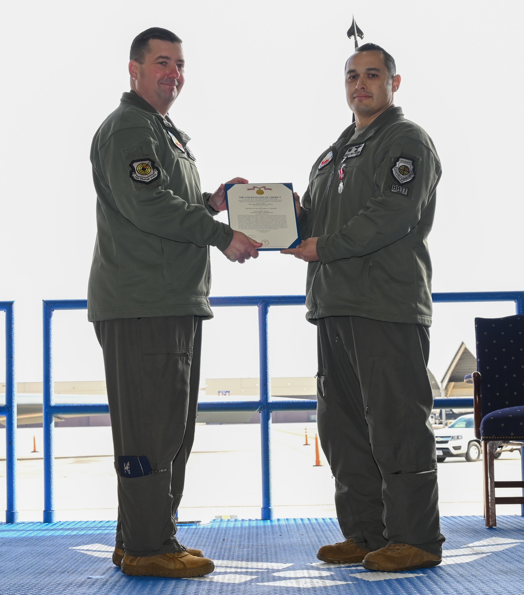 Lt. Col. Marcus Antonini, previous 325th Weapons Squadron, 57th Wing (right), and Col. Daniel Lehoski, United States Air Force Weapons School Commandant (left), pose with the Meritorious Service Medal certificate at Whiteman Air Force Base, Missouri, December 14, 2022. Change of commands are a military tradition of passing command from one commanding officer to another. (U.S. Air Force photo by Airman 1st Class Joseph Garcia)