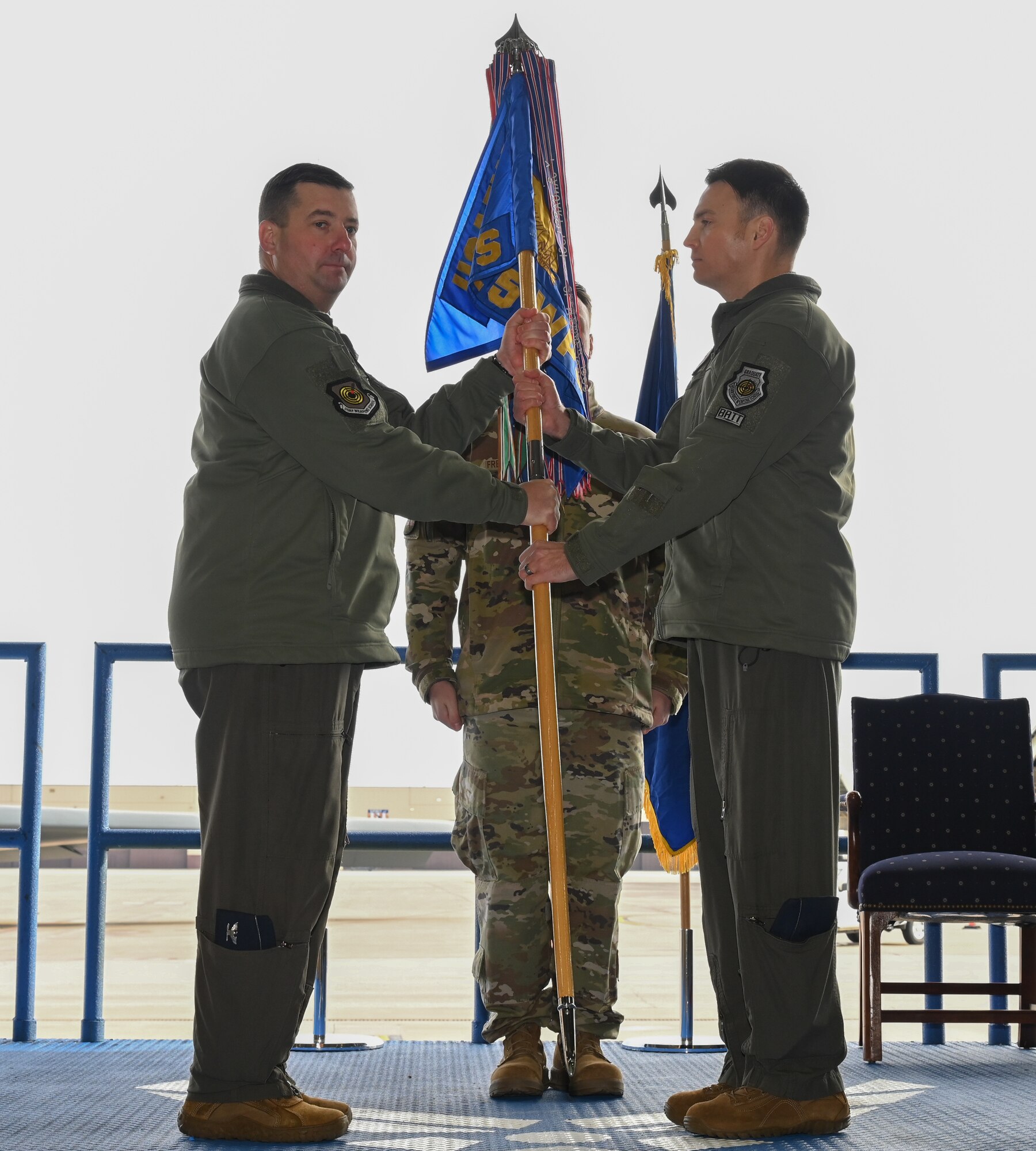 Col. Daniel Lehoski, United States Air Force Weapons School Commandant (left), passes the guidon to Lt. Col. Alexander Reich, 325th Weapons Squadron, 57th Wing (right), at Whiteman Air Force Base, Missouri, December 14, 2022. Change of commands are a military tradition of passing command from one commanding officer to another. (U.S. Air Force photo by Airman 1st Class Joseph Garcia)