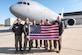 A group of military members pose for a photo in front of a jet