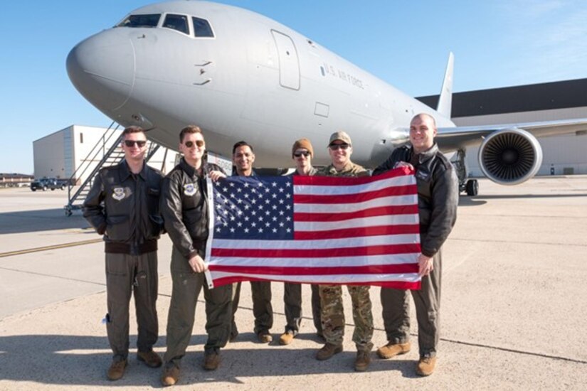 A group of military members pose for a photo in front of a jet