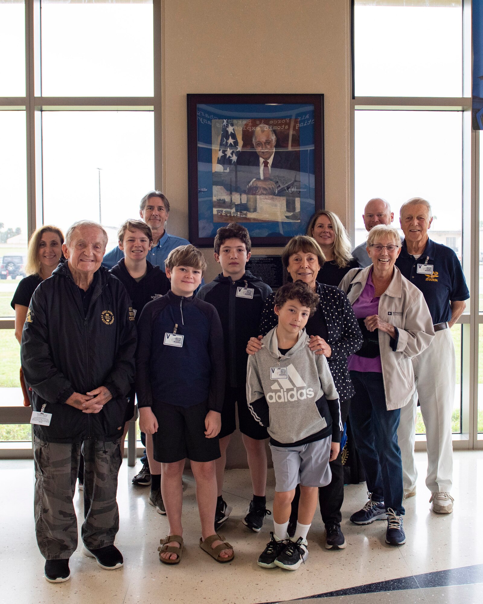 Family members of iconic leader and pioneer of long range detection Walt Singlevich pose for a group photo in front of Singlevich’s portrait and plaque dedicating the Department of Defense’s sole nuclear treaty monitoring center to AFTAC’s first Senior Scientist during the family’s visit to the center Nov. 22, 2022.  Pictured are Ellsworth Singlevich, Jonathan Lane, Trent Singlevich, Kimberly Lane, Brandon Lane, Spencer Singlevich, Melissa Singlevich, Sara Singlevich, Patrick Lane, Cynthia Singlevich, Paul Singlevich, and Jack Singlevich.  (U.S. Air Force photo by Matthew S. Jurgens)