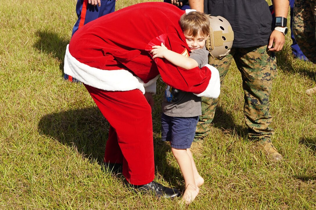 A Marine dressed as Santa hugs a boy during a Toys for Tots event.