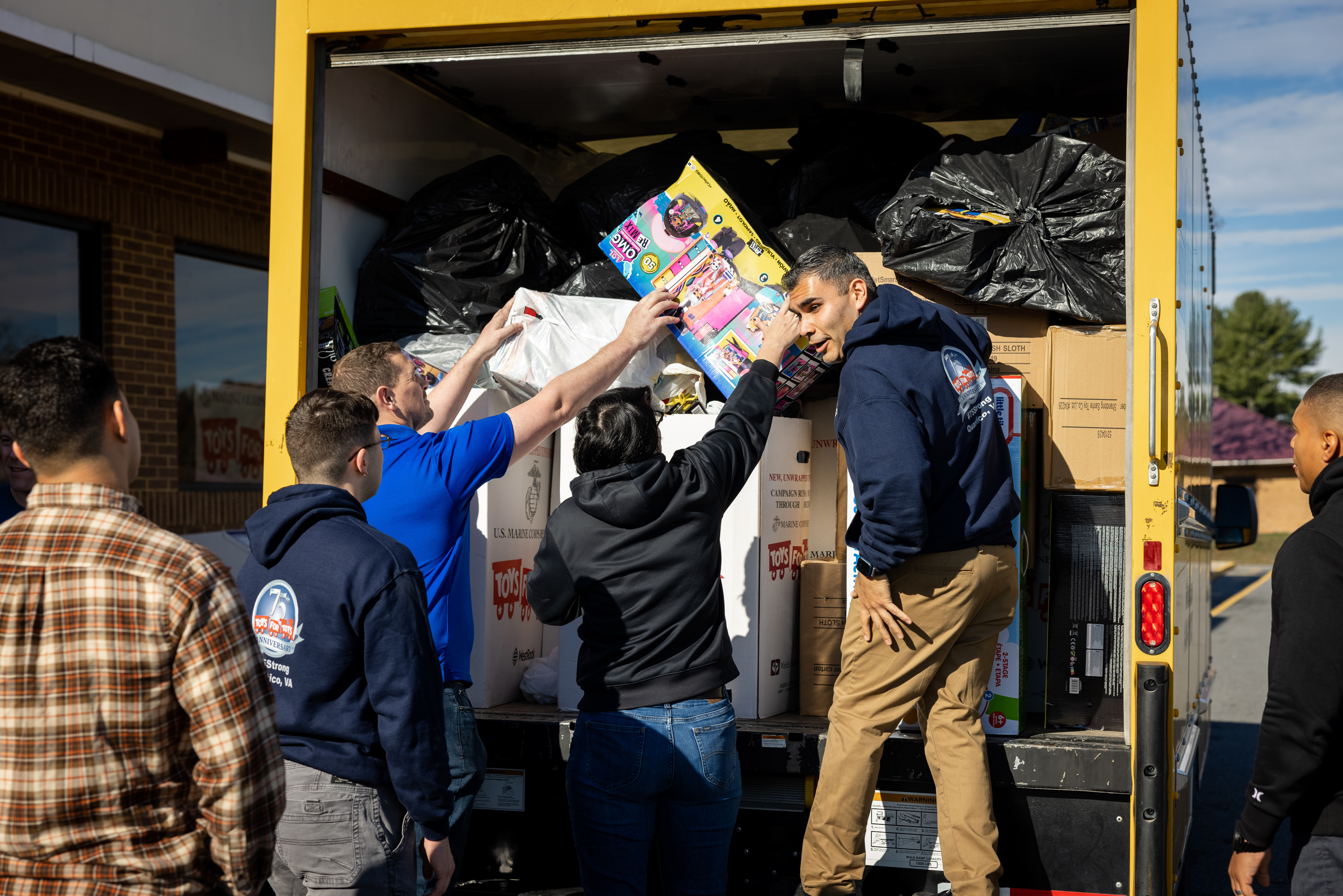 Marines unload Toys for Tots donations from the rear of a truck.