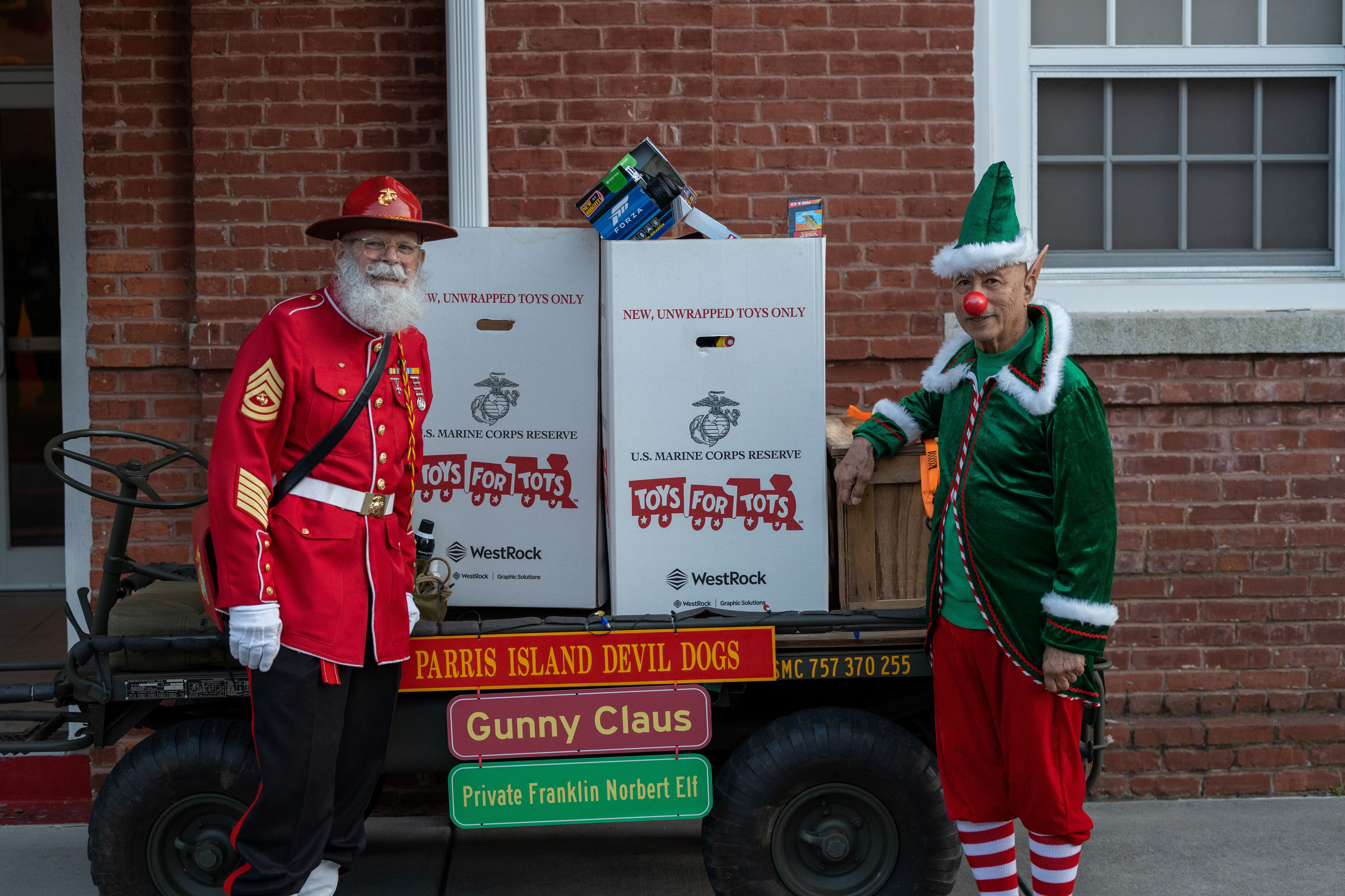 Marines dressed in Christmas-themed costumes pose with Toys for Tots donations.