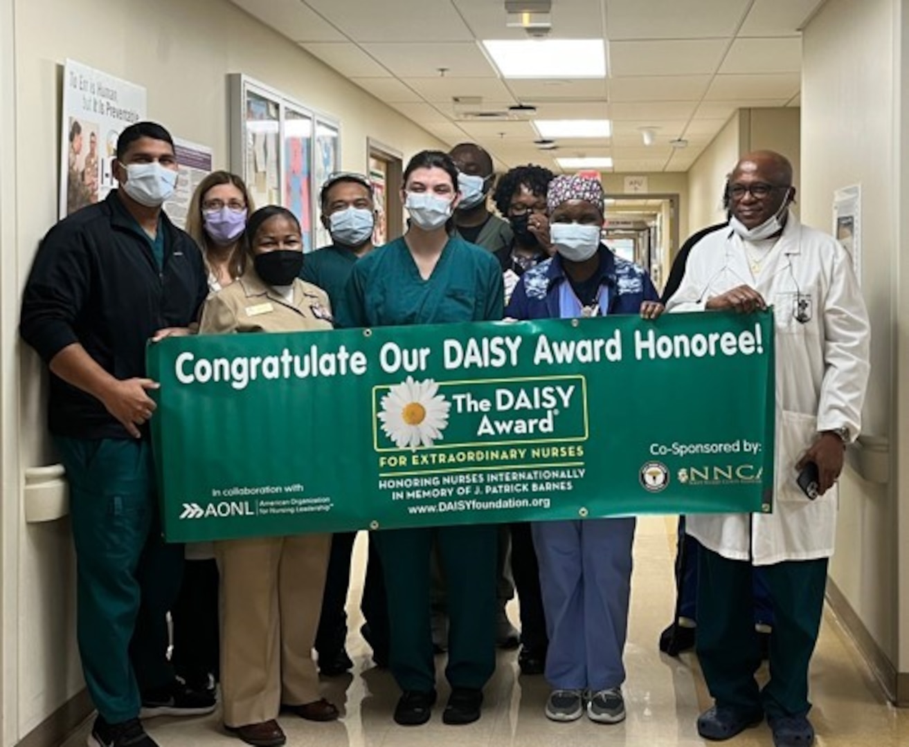 1st Lt. Maria Frisone, center, a nurse at Walter Reed National Military Medical Center (WRNMMC), is presented a commerative DAISY Award honoree banner at WRNMMC in Bethesda, Maryland. Frisone was nominated for The DAISY Award by a WRNMMC patient for professionalism, compassion, and attention to detail.