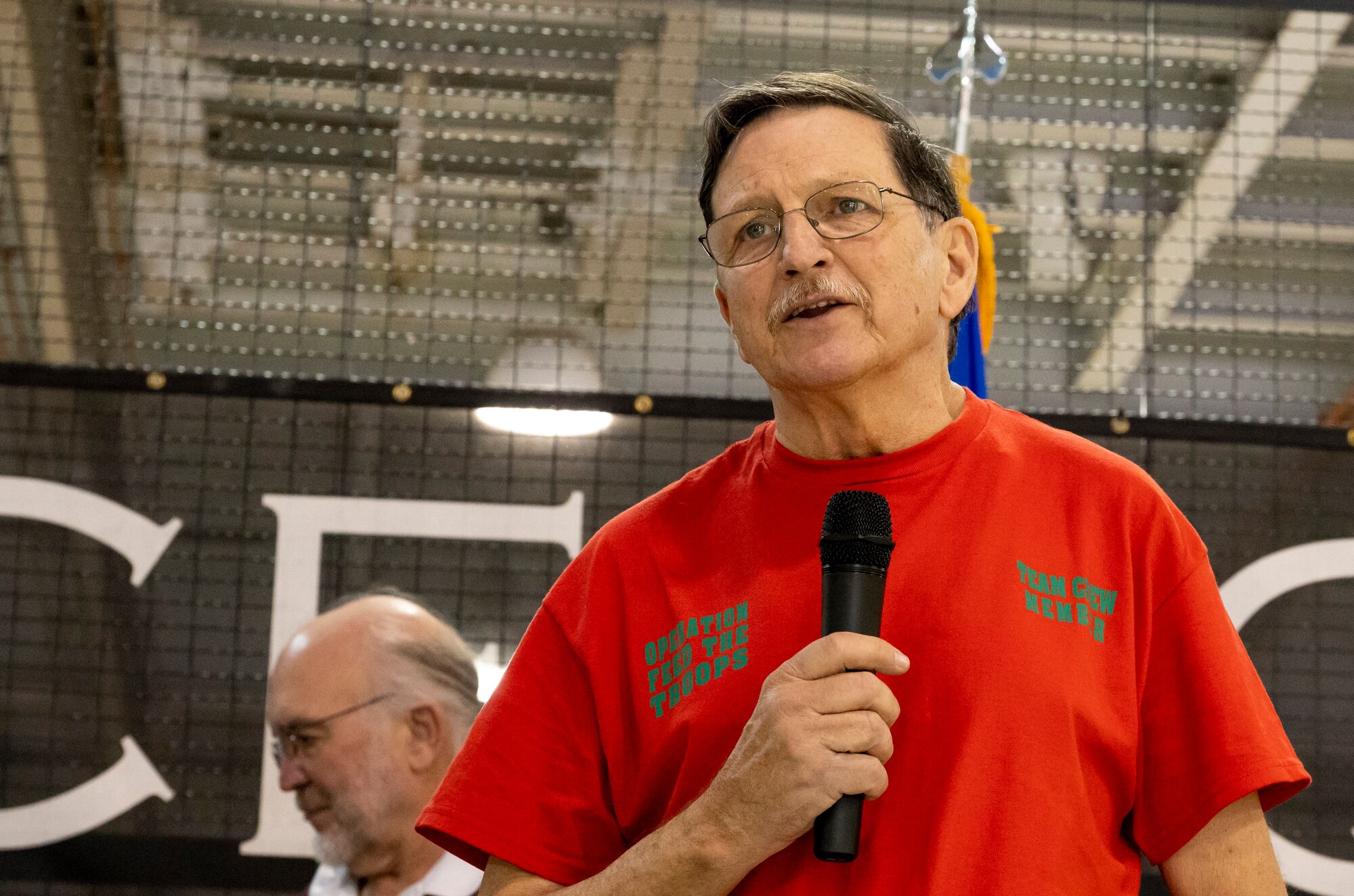 Bob Reese, founder and organizer of Operation Feed the Troops, announces the opening of the serving line during OFT on Dover Air Force Base, Delaware, Dec. 14, 2022. The 20th annual OFT featured a traditional holiday dinner, desserts, live music and a visit from Santa Claus. (U.S. Air Force photo by Senior Airman Stephani Barge)