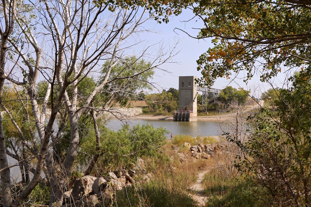 Reservoir control tower stands among trees at a lake in the fall.