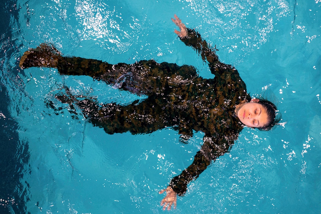 A Marine Corps recruit floats in a pool as seen from above.