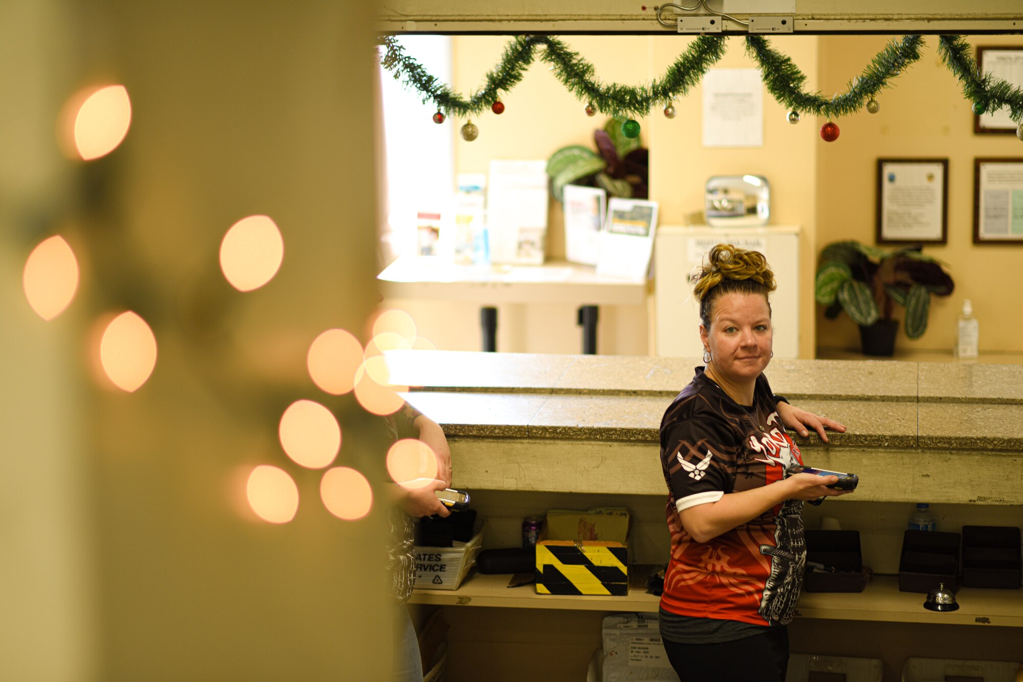 1st Sgt smiles at the camera holding post office scanner behind counter