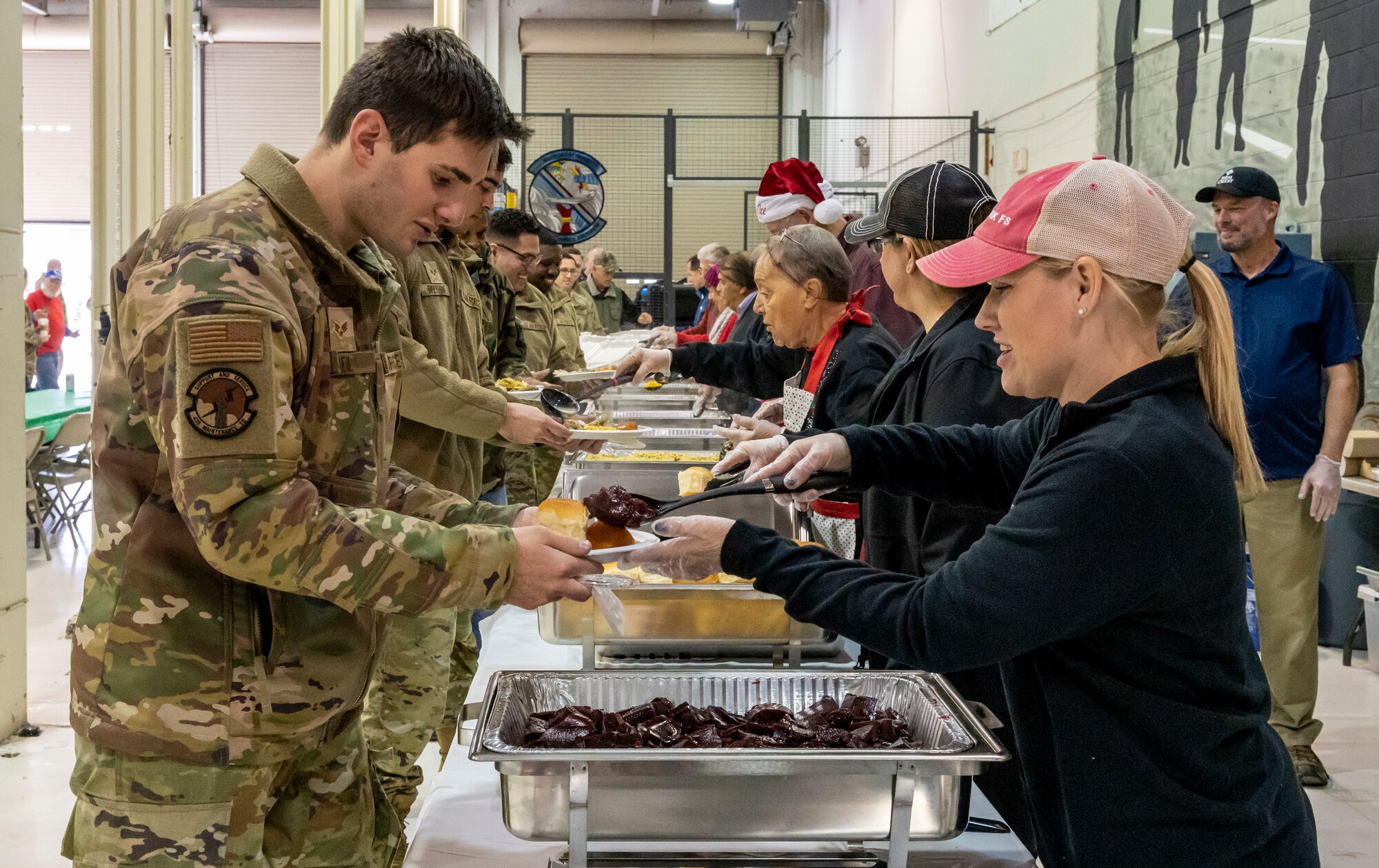 Senior Airman Michael Beil, 436th Maintenance Squadron crew chief, receives food during Operation Feed the Troops on Dover Air Force Base, Delaware, Dec. 14, 2022. OFT volunteers served a traditional holiday meal to members of Team Dover during lunch and dinner meal times. Seventy turkeys were prepared and donated by local businesses for the event. (U.S. Air Force photo by Senior Airman Stephani Barge)