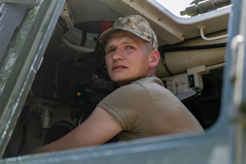 A soldier sits inside a combat vehicle.