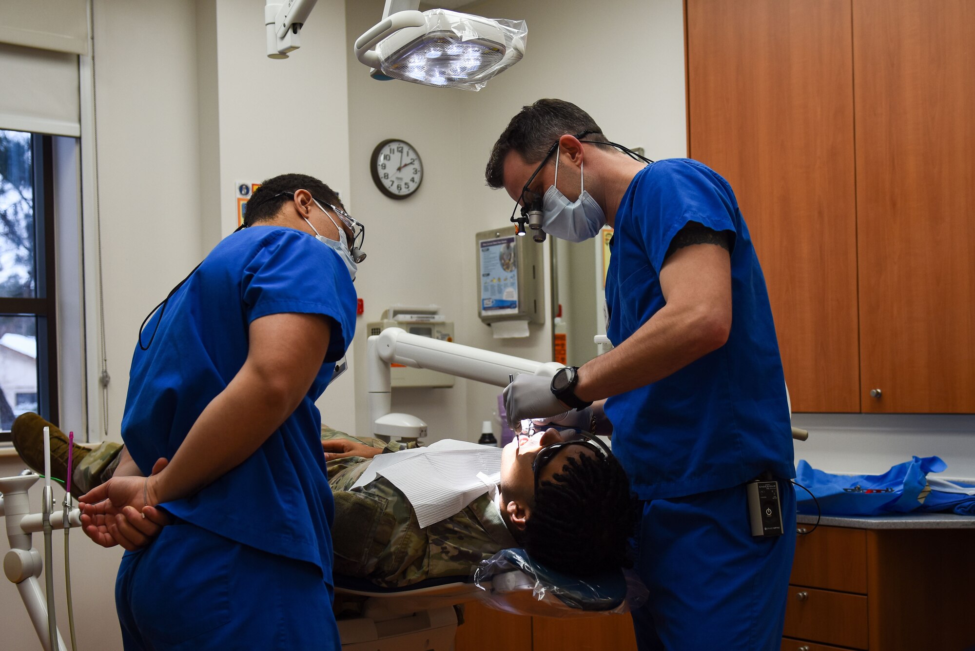 Senior Airman Malik Veveiros, 8th Operational Medical Readiness Squadron dental technician (left), observes as Dr. (Capt.) Clifton Wright, 8th OMRS general dentist, conducts an exam on a patient at Kunsan Air Base, Republic of Korea, Dec. 14, 2022. At the end of a cleaning procedure, the dentist will review the dental technician’s cleaning and identify any additional issues. (U.S. Air Force Photo by Tech. Sgt. Timothy Dischinat)