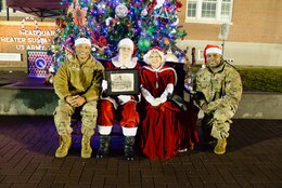 Maj. Gen. Michel M. Russell Sr. and Command Sgt. Maj. Albert E. Richardson sit with Santa and Mrs. Claus