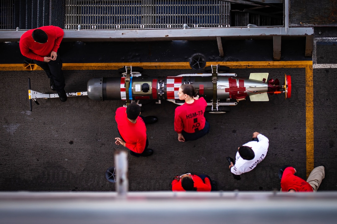 An overhead picture of sailors inspecting a weapon on a ship.