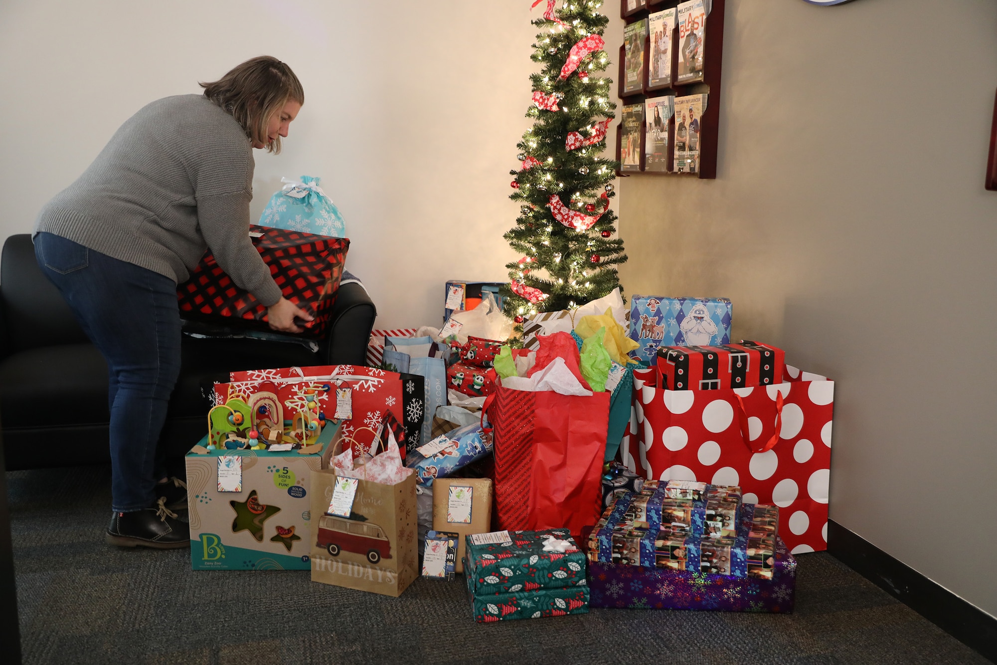 Ms. Shanna King, director of the 445th Military and Family Readiness Center, places a gift by the Angel Tree in the M&FR center at Wright-Patterson Air Force Base, Ohio, as donations are dropped off, Dec. 3, 2022. (U.S. Air Force photo/Capt. Rachel Ingram)