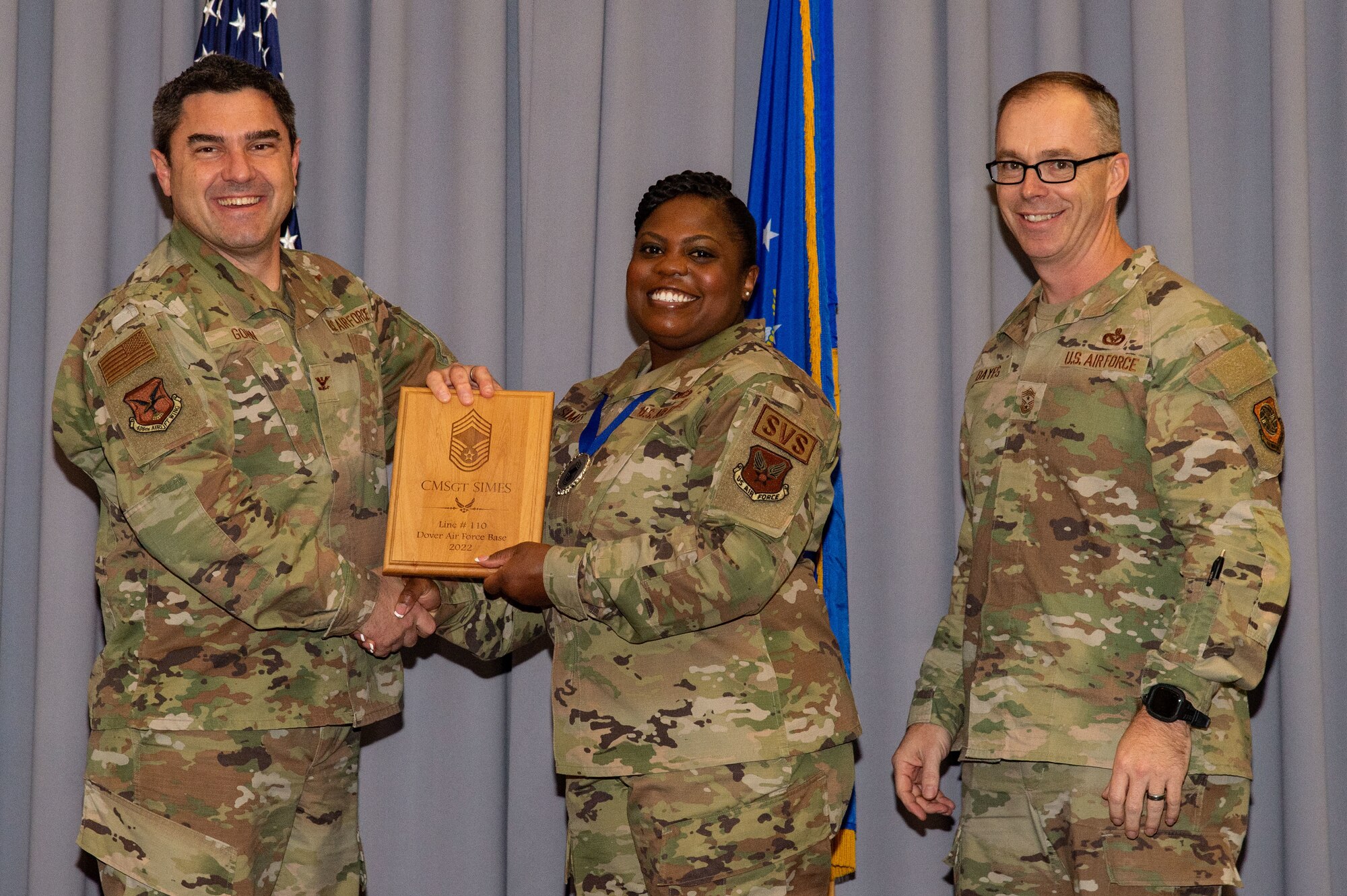 Col. Rusty Gohn, left, 436th Airlift Wing vice commander, and Chief Master Sgt. Timothy Bayes, right, 436th AW command chief, present Chief Master Sgt.-select Shonta Simes, Air Force Mortuary Affairs Operations superintendent of operations support, with a plaque noting her promotion to chief at The Landings on Dover Air Force Base, Delaware, Dec. 8, 2022. Senior Master Sgt. Simes was one of 514 Airmen selected for promotion to the top enlisted rank of chief. (U.S. Air Force photo by Roland Balik)