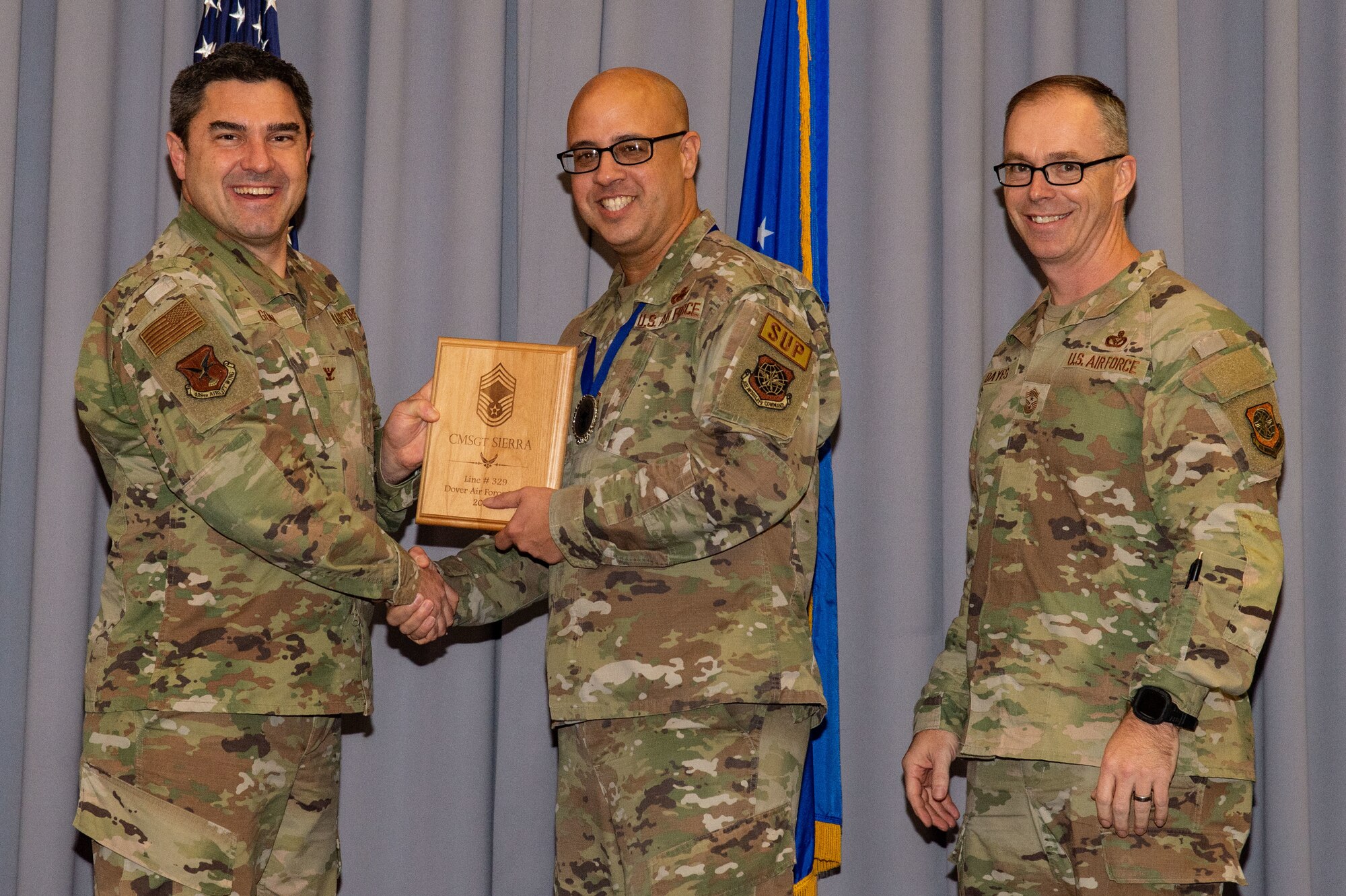 Col. Rusty Gohn, left, 436th Airlift Wing vice commander, and Chief Master Sgt. Timothy Bayes, right, 436th AW command chief, present Chief Master Sgt.-select Michael Sierra, 436th Logistics Readiness Squadron material management flight superintendent, with a plaque noting his promotion to chief at The Landings on Dover Air Force Base, Delaware, Dec. 8, 2022. Senior Master Sgt. Sierra was one of 514 Airmen selected for promotion to the top enlisted rank of chief. (U.S. Air Force photo by Roland Balik)